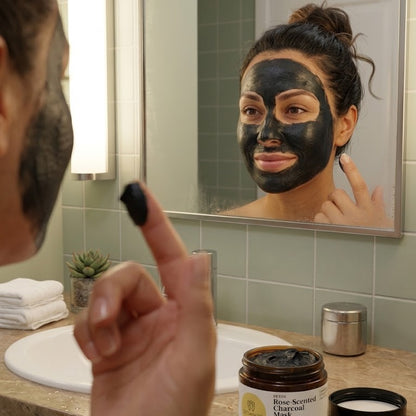 Woman applying Rose-Scented Charcoal Mask evenly across face for deep pore cleansing and oil control treatment