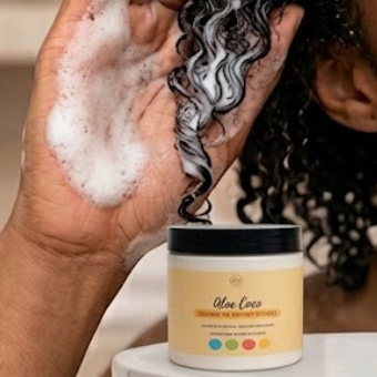 Person applying aloe vera hair care product to their hair with a jar of the product in the foreground.