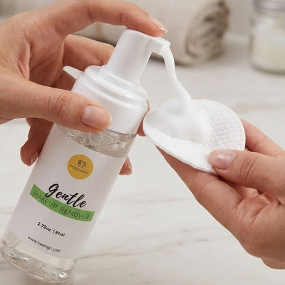 Person holding a bottle of gentle cleanser with a white applicator on a bathroom counter.